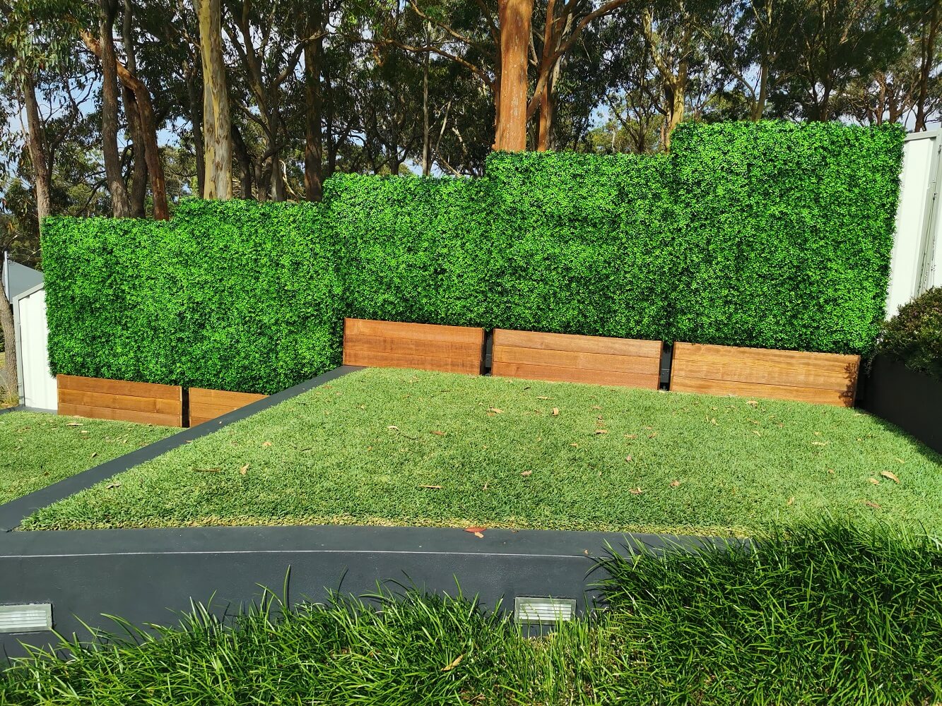 Artificial boxwood hedge installed onto a timber planter base outdoors