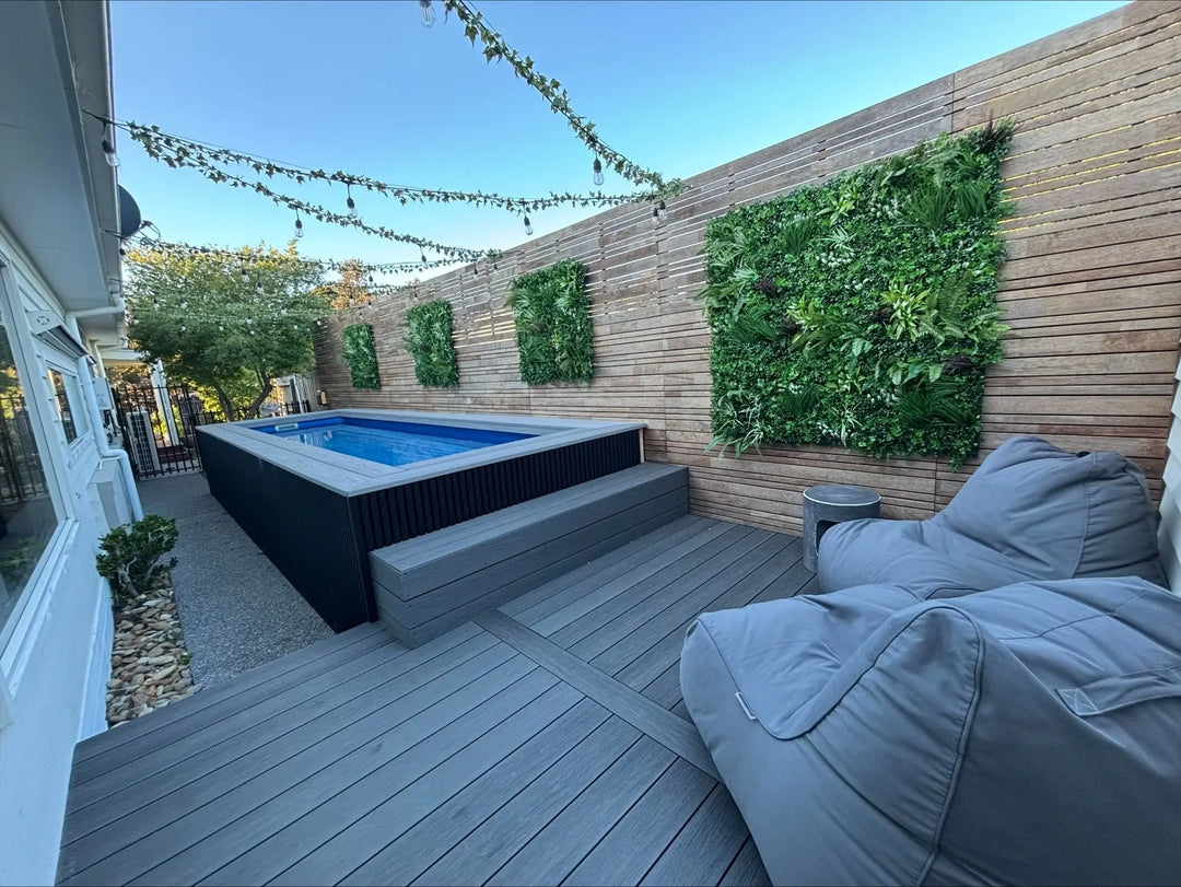 Modern outdoor deck with pool, vertical garden wall, outdoor bean bags, and string lights.