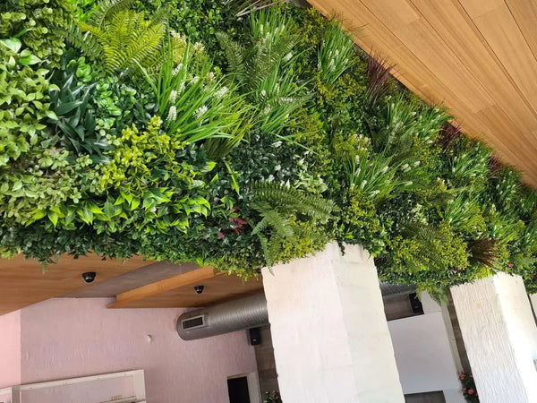Artificial green wall running beneath a timber ceiling in a hotel