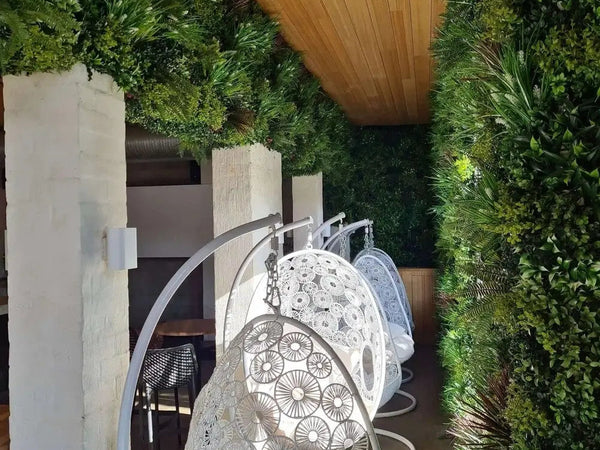 Hanging chair and white columns between artificial green walls in a hotel lounge