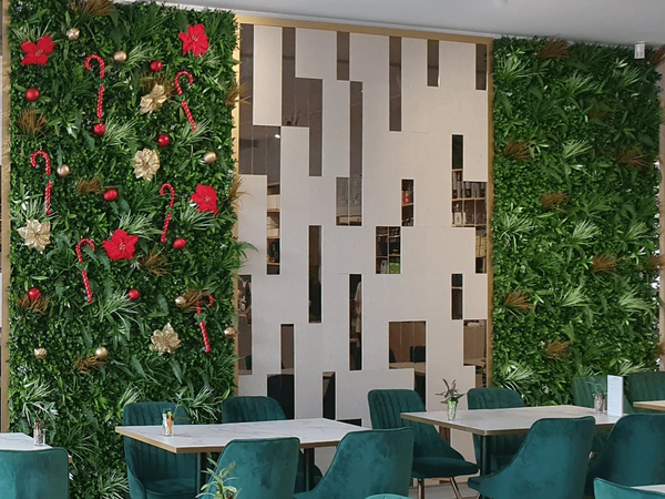 Restaurant dining area with teal chairs beside artificial green walls with red flowers