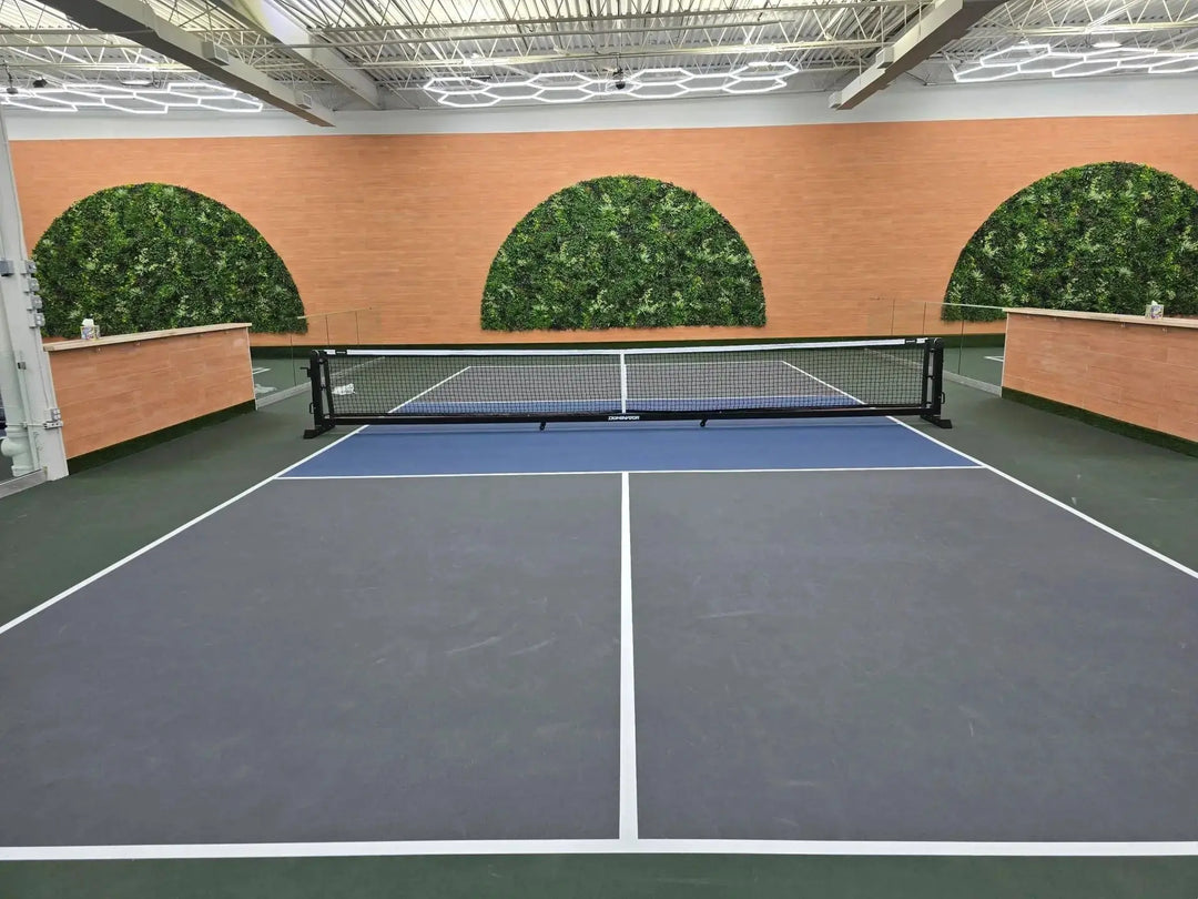 Indoor pickleball playing field with circle green wall in background.
