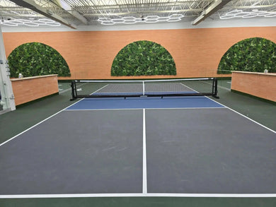 Indoor pickleball playing field with circle green wall in background.