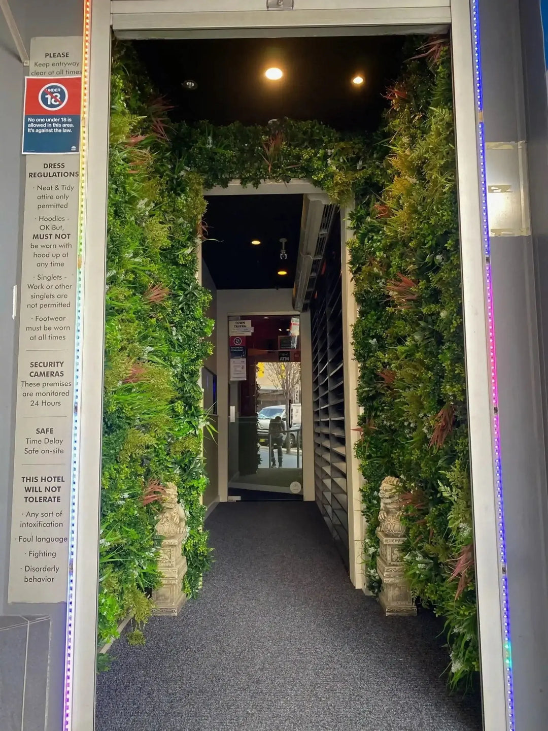Decorative indoor garden with plants on either side of a doorway leading to a club.
