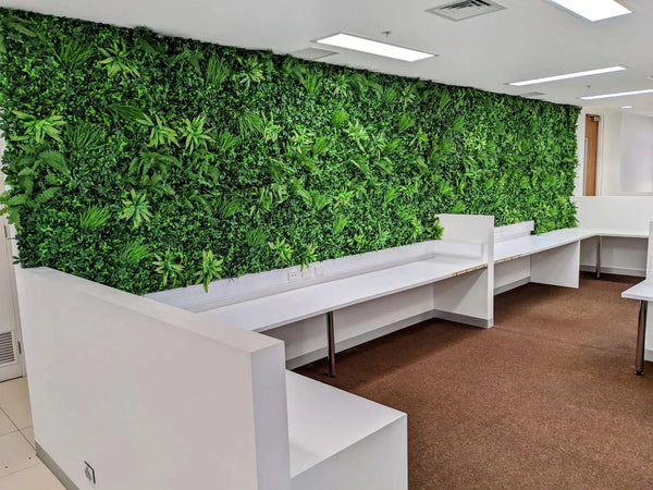 Long artificial green wall above white desks in an office
