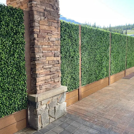 Close-up view of artificial plant wall panels next to a stone pillar.