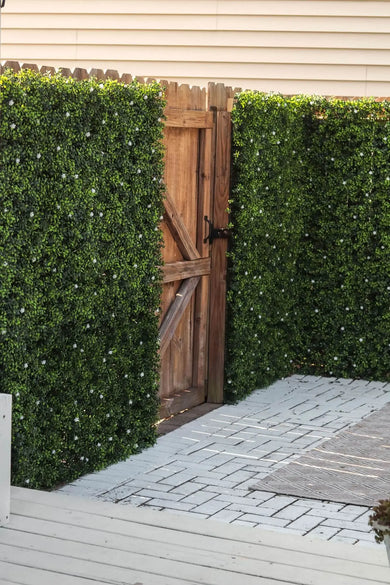 Artificial Boxwood Mat with Faux Flowers Installed Outdoors onto a Fence