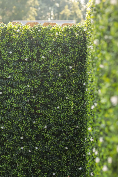 Artificial Boxwood Mat with Faux Flowers Installed Outdoors onto a Fence with White Flowers