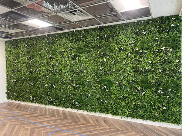 Floor-to-ceiling artificial green wall along an office wall with timber floors