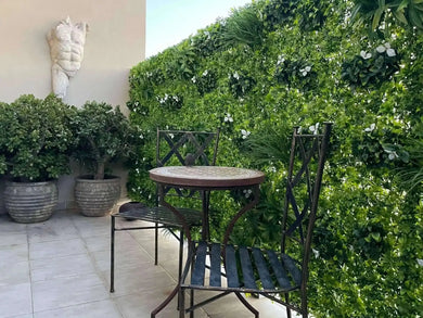Small outdoor patio with a round table and two chairs surrounded by greenery.