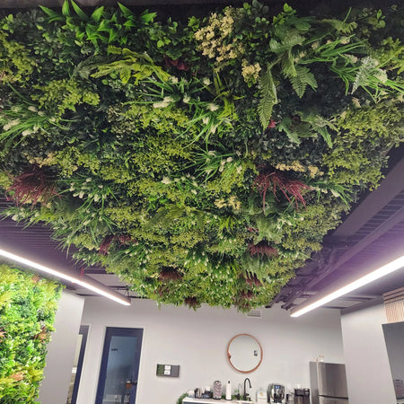 Artificial vertical garden panels installed across a ceiling above an office area.