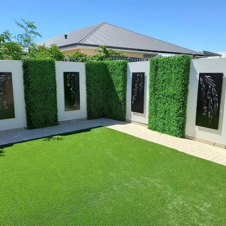 Courtyard lawn framed by artificial hedge panels with decorative inserts.