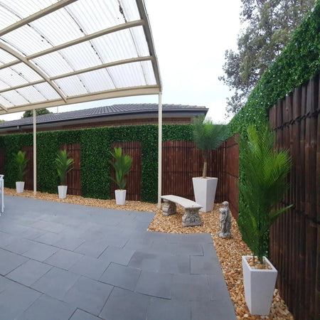 Covered patio with artificial hedge panels along the boundary fence.