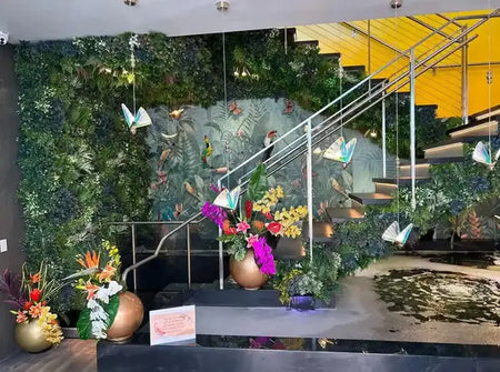Tropical artificial green wall with butterfly decor and orchids beside an office staircase.