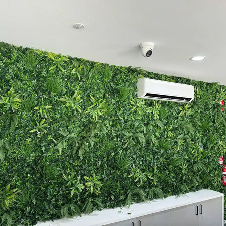 Large mixed-foliage artificial green wall covering an office wall above a low cabinet.