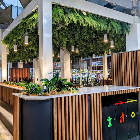 Outdoor bar with wood slats and artificial hanging greenery along the canopy.