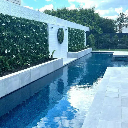 Artificial green wall above a white pool wall with a water feature.
